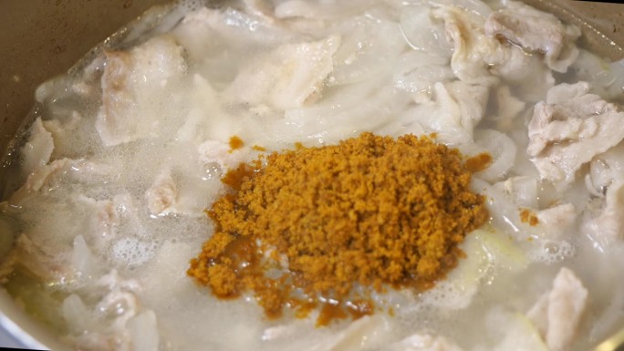 在热水中煮熟的猪肉和洋葱中加入咖喱粉的视频。