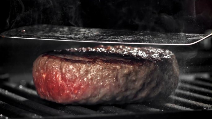 用天然肉类制成的汉堡在煎锅里煎。用高速摄像机拍摄，每秒1000帧。