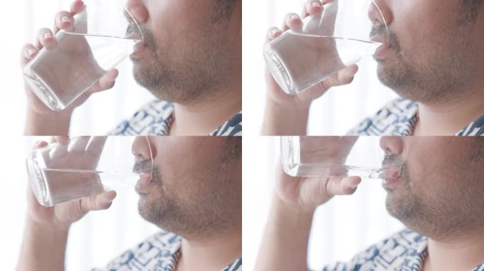 38岁的亚洲男人在家里闭口喝一杯淡水。用健康的生活习惯开始新的一天，用干净的矿物质自然静水。生活保健