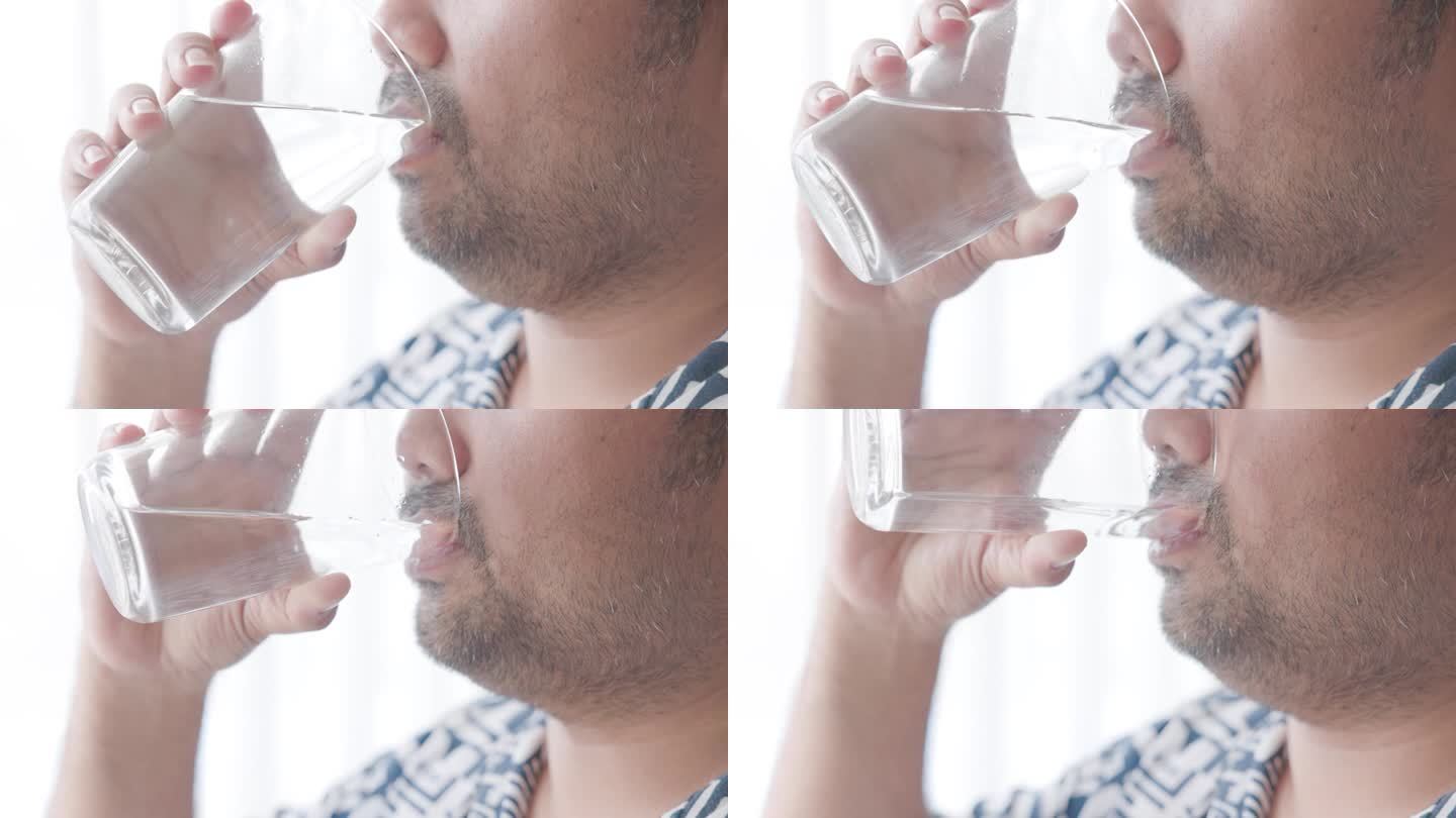 38岁的亚洲男人在家里闭口喝一杯淡水。用健康的生活习惯开始新的一天，用干净的矿物质自然静水。生活保健