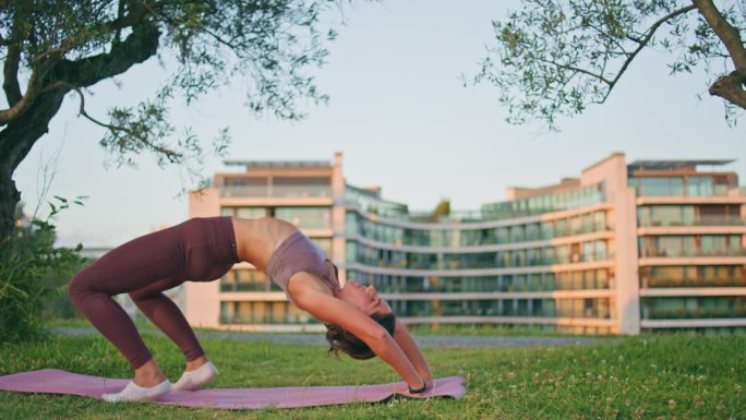 柔韧的女子在阳光公园表演桥牌姿势。修身女士练瑜伽