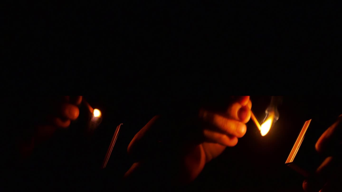 如何划火柴。缓慢的运动。男人点起了灯，在黑暗中拿着火柴盒和燃烧着的火柴。以96 fps录制，以25f