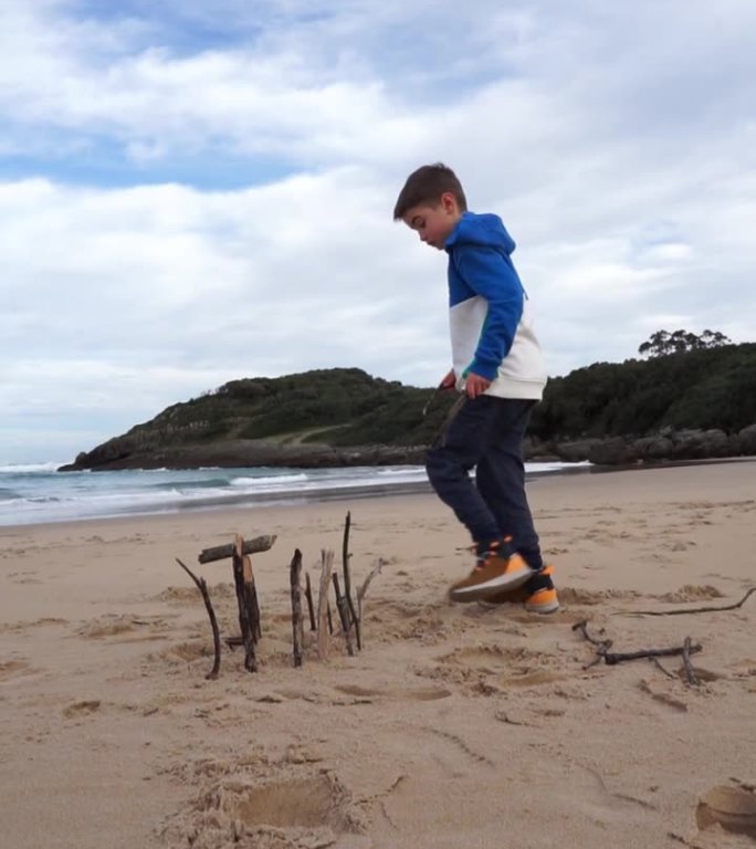 冬天，孩子在沙滩上玩沙子，用一些木棍搭房子