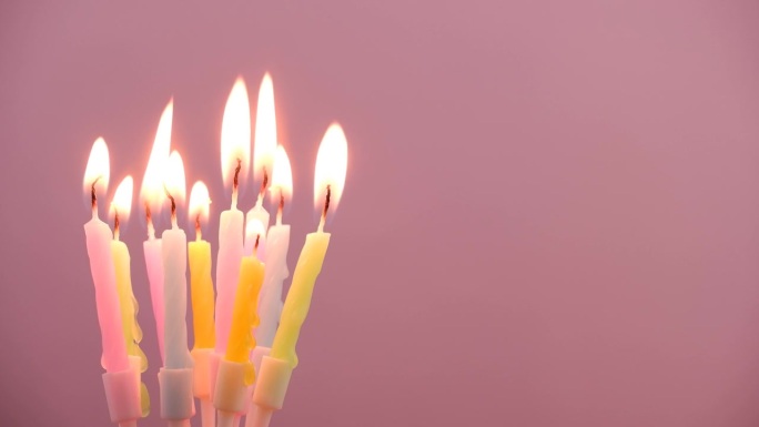 生日蜡烛燃烧在粉红色的背景，文字的复制空间。