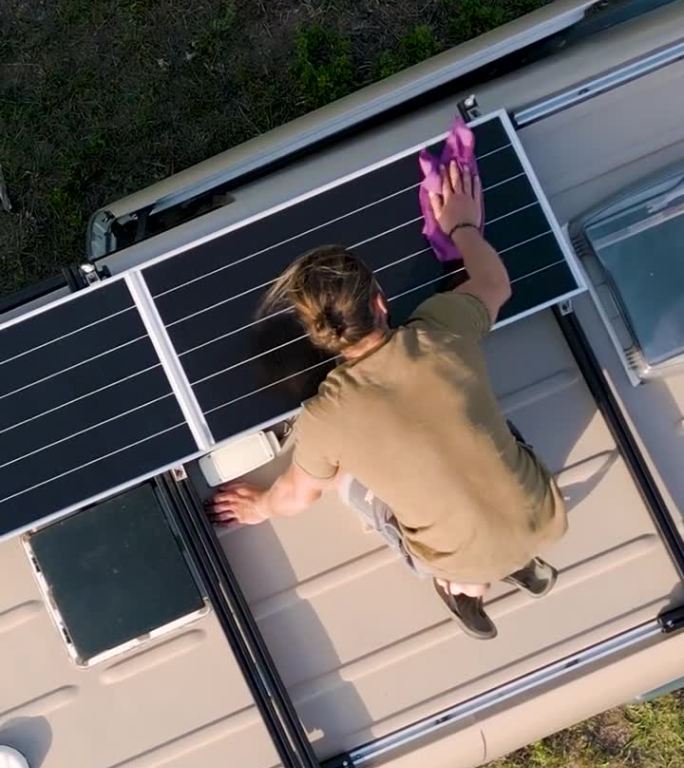 鸟瞰图:一名男子正在清洁露营车车顶上的太阳能电池板