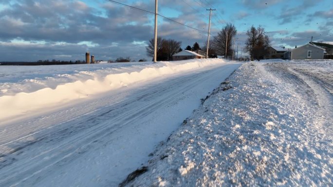 冬雪沿着乡间小路飘来飘去。危险驾驶条件与暴风雪条件在美国乡村农场场景。扫雪机打开街道。鸟瞰图。