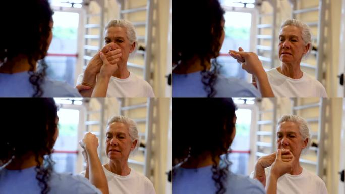 理疗师在理疗的某一动作中，在一位老妇人表示疼痛时，正在检查她的手