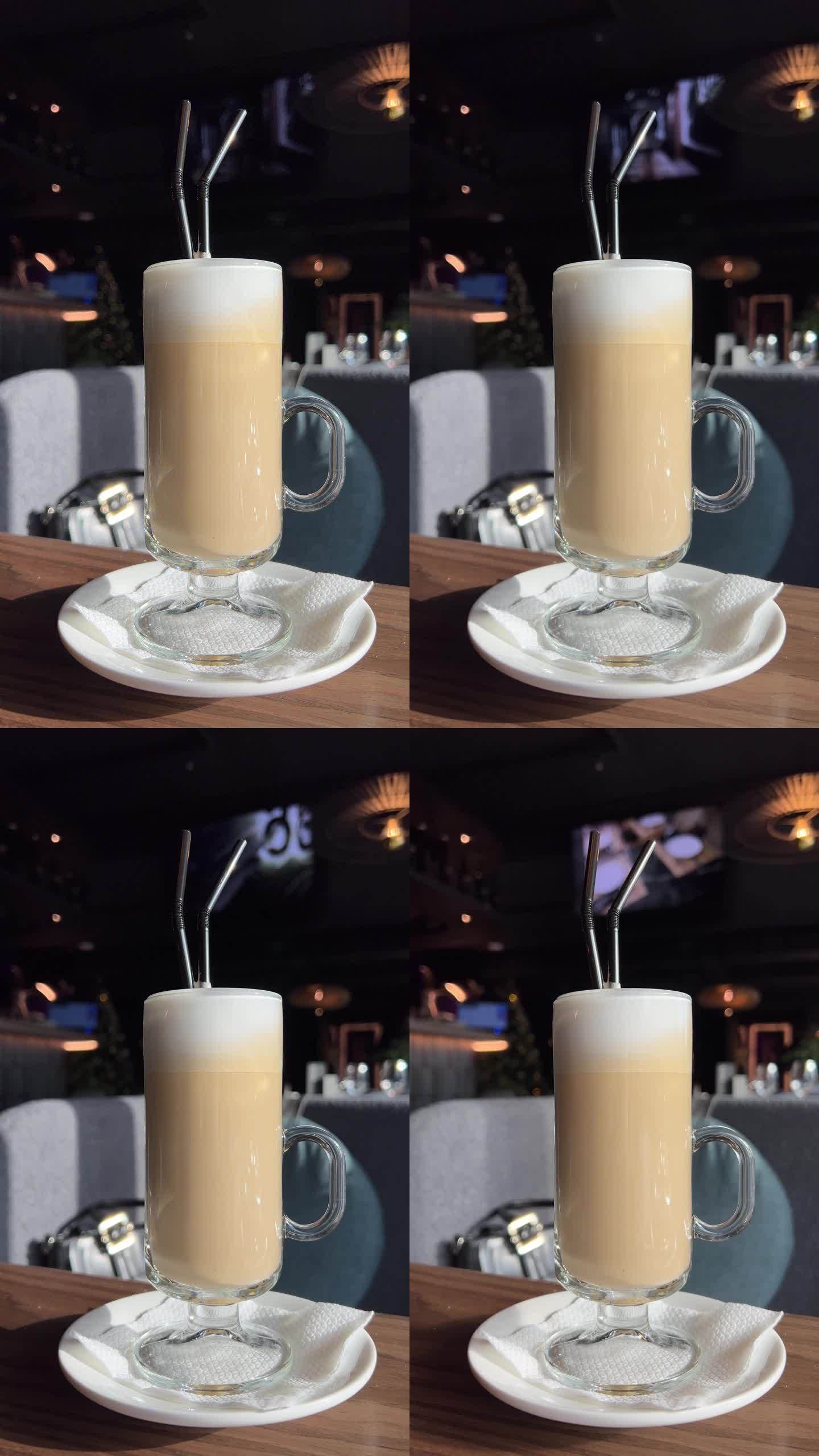 咖啡馆里木桌上的一杯玻璃杯咖啡。咖啡上的叶子拉花艺术。咖啡店里的纯素豆浆饮料