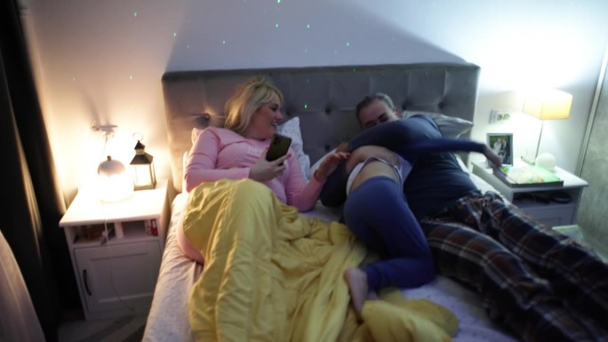 当父亲和儿子在床上玩耍时，女人在玩手机