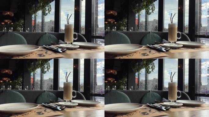 咖啡馆里木桌上的一杯玻璃杯咖啡。咖啡上的叶子拉花艺术。咖啡店里的纯素豆浆饮料