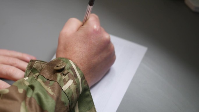 一个陆战队员用一支笔在一张纸上写信