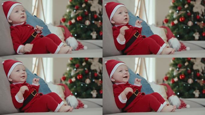 快乐可爱的小男孩穿着圣诞老人的服装坐在家里的沙发上过圣诞节。圣诞快乐，新年快乐，童年快乐，节日快乐，