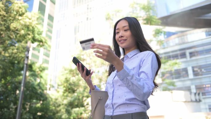 在城市中使用智能手机的中国或亚洲混血女商人。