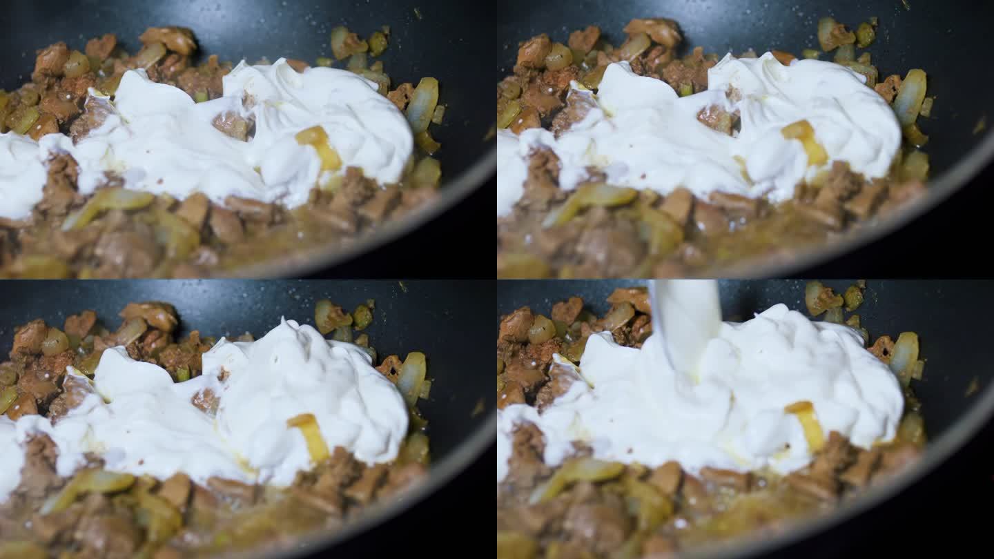 用勺子在炸好的鸡肝和洋葱中加入酸奶油。