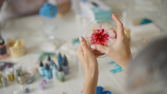 女性手握着透明环氧树脂艺术树脂制成的美丽工艺品，里面有盛开的红花