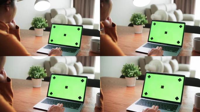 年轻的亚洲女性在家里客厅工作时使用绿屏笔记本电脑的特写