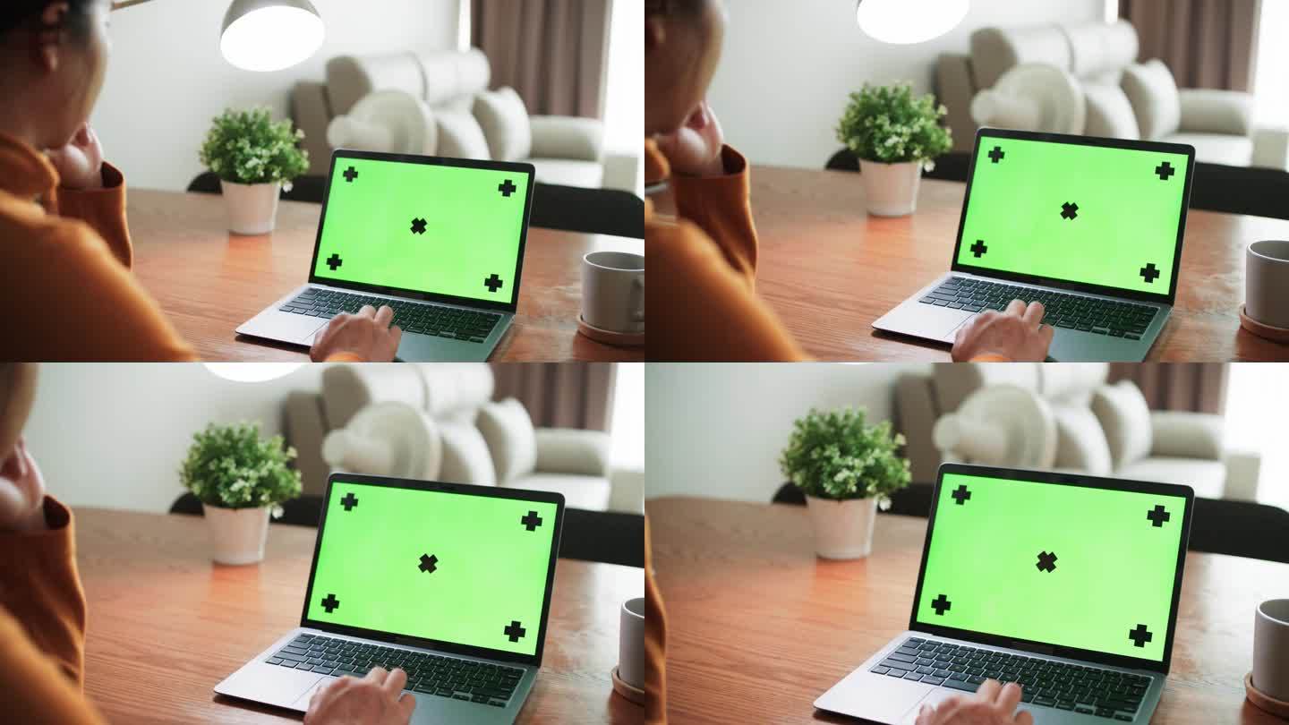 年轻的亚洲女性在家里客厅工作时使用绿屏笔记本电脑的特写