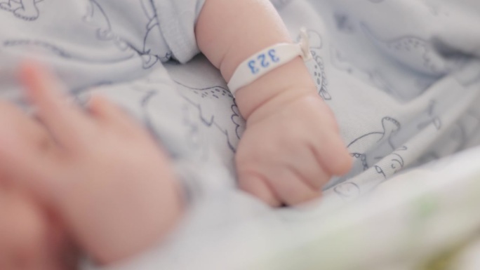 新生儿戴着识别手镯躺在妇产医院的婴儿床上的特写镜头