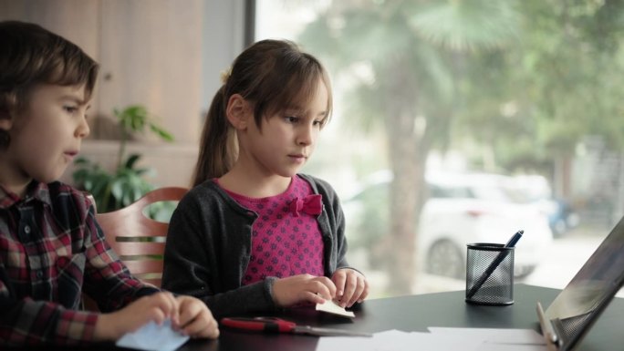 孩子们按照数码平板电脑视频教程中的步骤，用彩色纸做折纸玩具