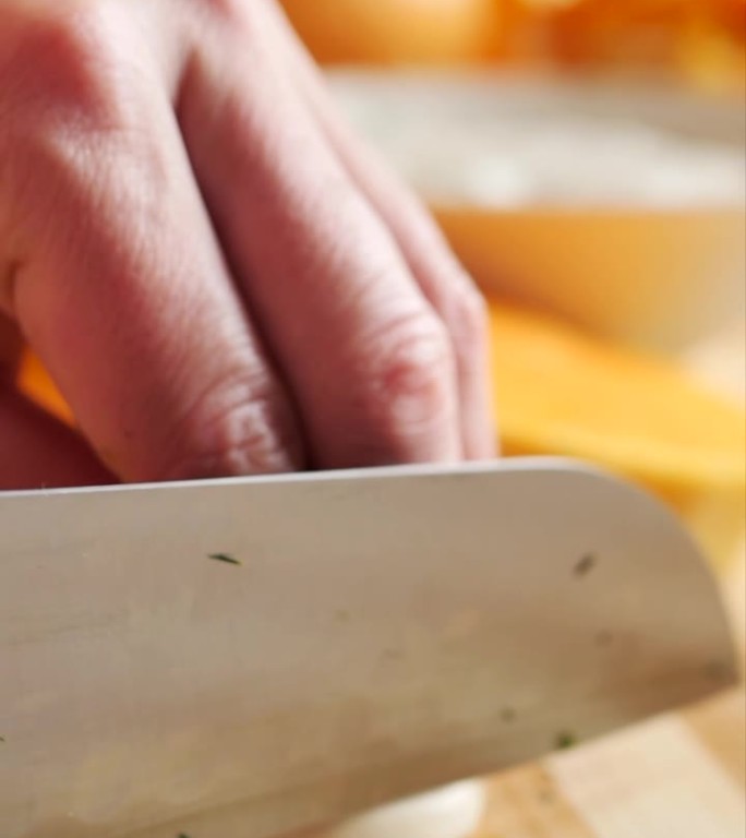 女性的手用菜刀和砧板压碎一瓣大蒜，用手用力按压，用锋利的宽菜刀将大蒜切成小块。垂直