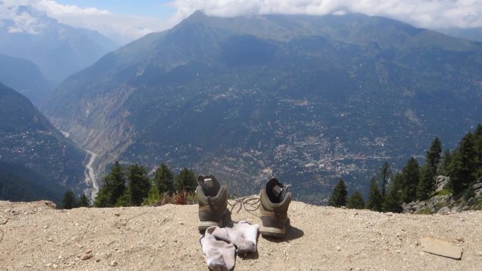 在印度喜马偕尔邦度过了漫长的一天后，徒步旅行的鞋子凝视着山谷和山脉，这是一张创造性的照片。