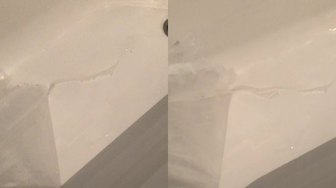 一个新浴缸的垂直特写，一只手从它的表面取下聚乙烯保护罩。享受新购买的家庭设施。