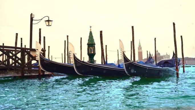 在威尼斯柔和的日出中，巨大的浪花飞溅，一盏绿色的灯笼在摇曳的贡多拉上画着十字架，一盏灯笼矗立在蔚蓝的