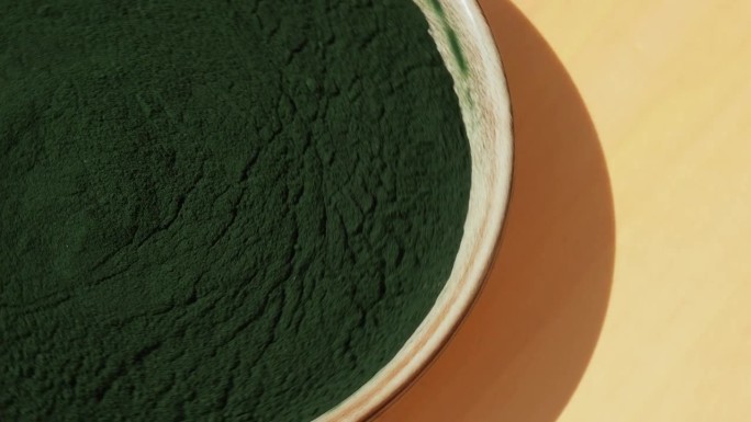 旋转有机蓝绿藻螺旋藻粉餐盘。小球藻对健康的益处。维生素和矿物质。排毒膳食补充剂海藻超级食品