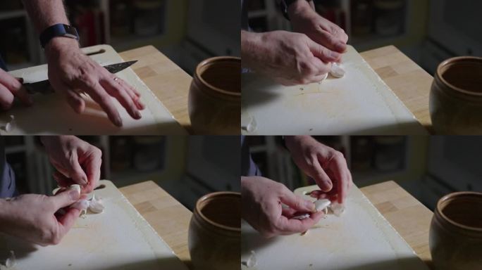 在自然光下，双手用厨刀在砧板上，在现代厨房的肉店柜台上压碎蒜瓣