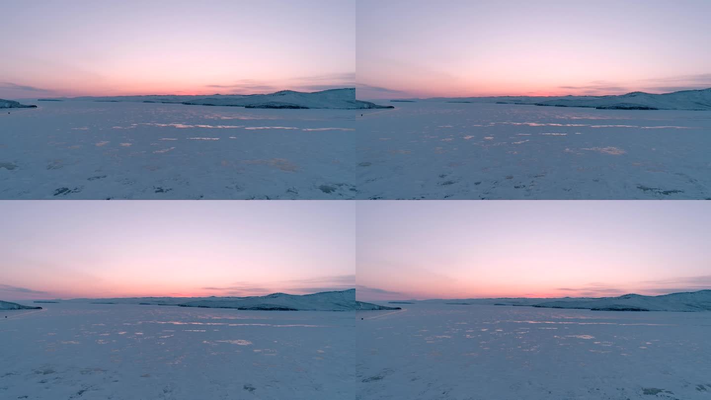 从空中俯瞰冰冻的贝加尔湖，欣赏美丽的粉橙色日出。太阳在冰面上的反射。贝加尔湖冰冻的冬季景观
