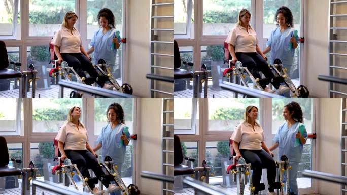 一个成熟的女人在康复中心的理疗师的帮助下，在机器上锻炼她的腿