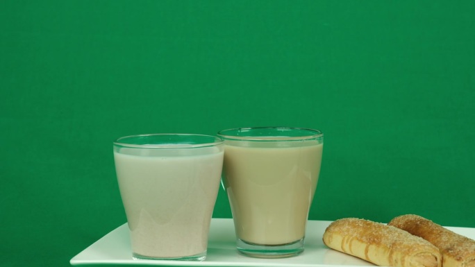 广告绿色背景镀铬复制空间两杯拿铁咖啡和一个牛角面包在桌子上。餐馆街头小吃的生活方式。