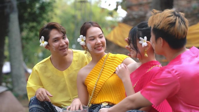 在泰国泼水节期间，一群穿着传统泰国服装的年轻人愉快地交谈。
