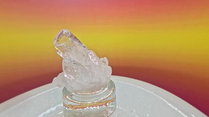 一个石英水晶石在一个模糊的彩色背景旋转的特写镜头