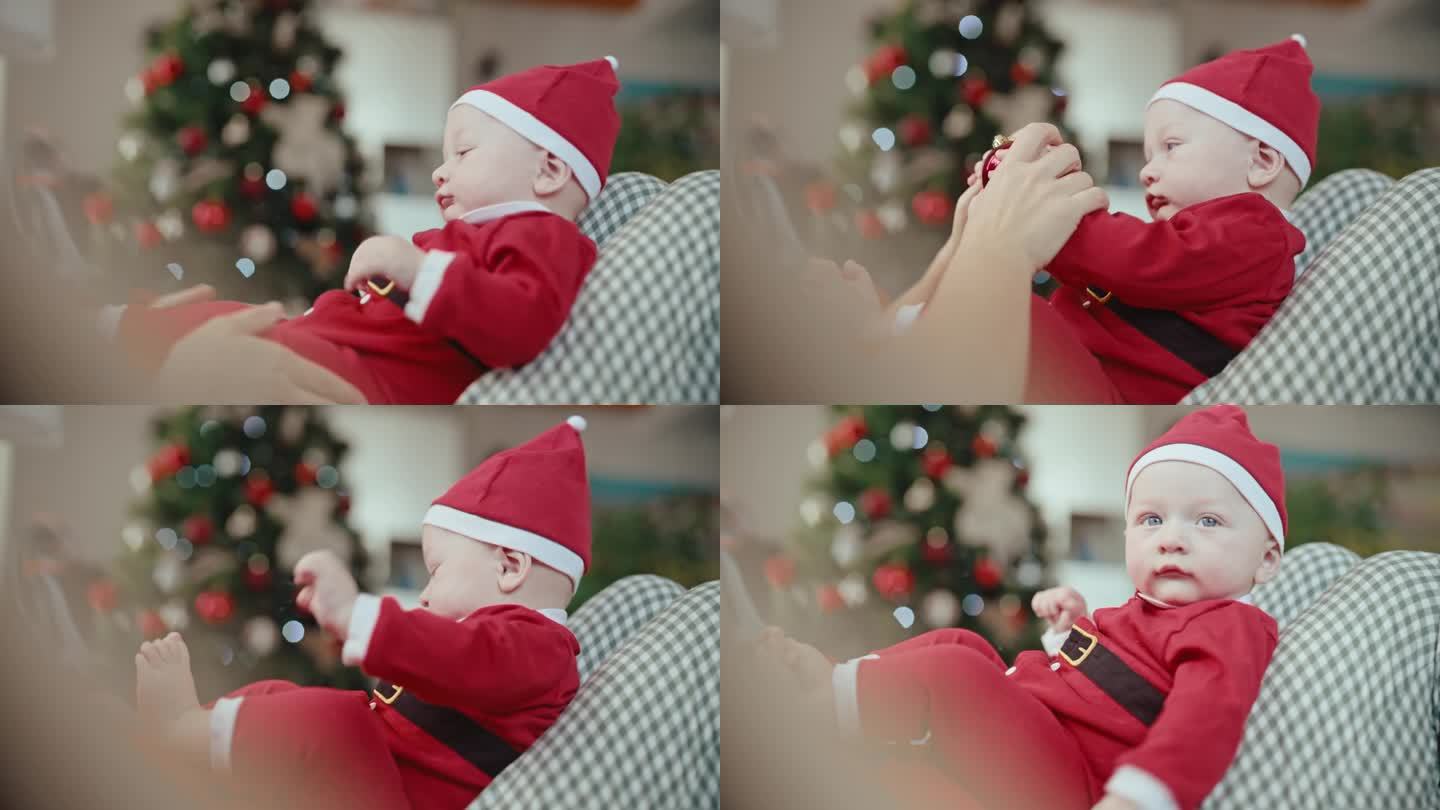 穿着圣诞老人服装的可爱小男孩坐在妈妈身上玩小玩意的手持照片