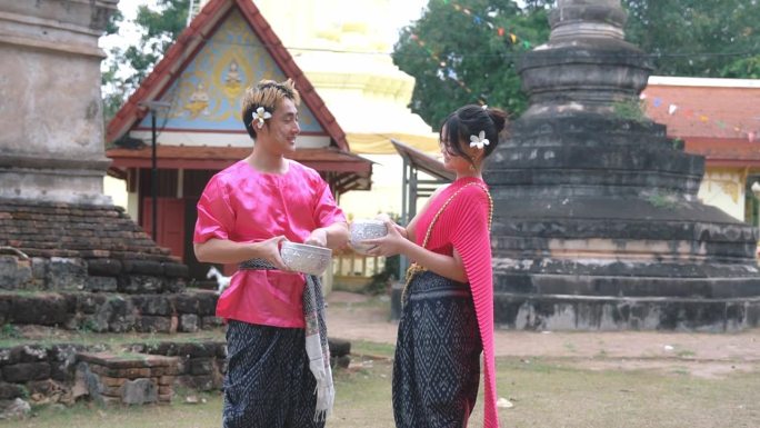 在泼水节期间，一对穿着传统泰国服装的夫妇在水里玩耍。