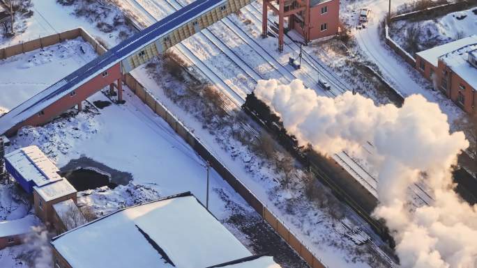 航拍中国东北冬季雪景中的蒸汽火车穿过村庄