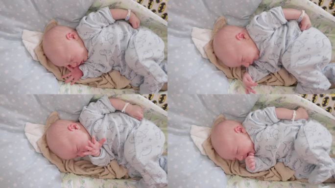 在妇产医院，刚出生的男婴在婴儿床上睡觉时打哈欠和伸懒腰。一个5天大的婴儿