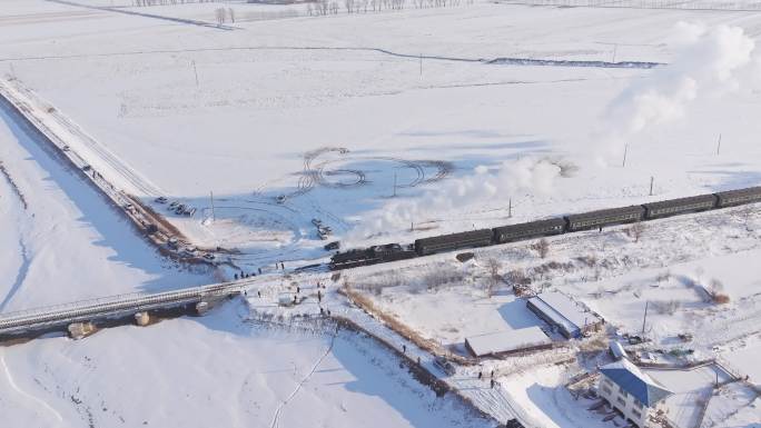 航拍中国东北冬季雪景中的蒸汽火车穿过村庄