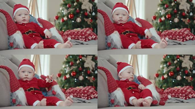 可爱活泼的小男孩穿着圣诞老人的服装，坐在家里的沙发上玩玩具