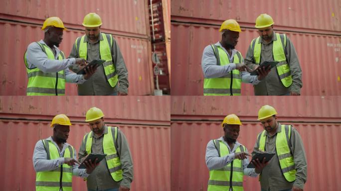 两名身穿安全制服的工业工人在仓库一起检查平板上的容器。黑人男性主管和印度工业工程师在平板电脑上交谈。
