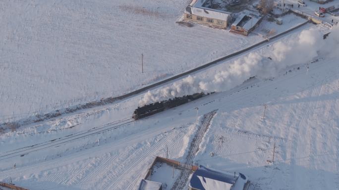 航拍中国东北冬季雪景中的蒸汽火车穿过村庄