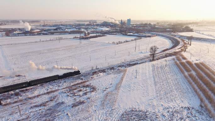 航拍中国东北冬季雪景中的蒸汽火车穿过村庄