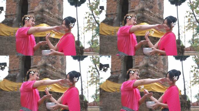 一个年轻男子礼貌地给年轻女子搽粉。在泰国宋干节期间。