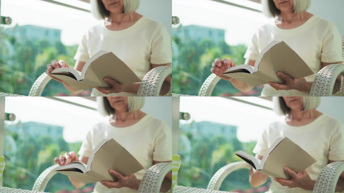 坐在阳台上看书的亚洲老年妇女