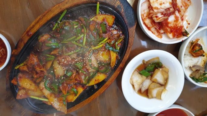 当地韩式美食热盘滋滋滋的猪器官头内脏和皮肤辣酱配菜俯视图慢动作