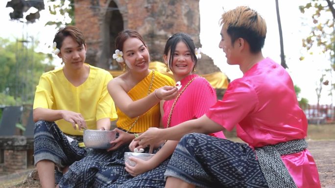 在泰国泼水节期间，一群穿着传统泰国服装的年轻人愉快地交谈。