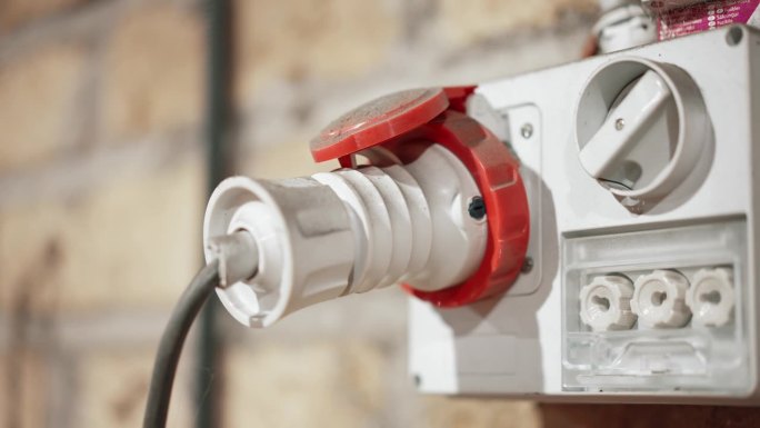白色电源插座外墙上带插头，高压三相电源，用于五金工业，电源和电力的概念