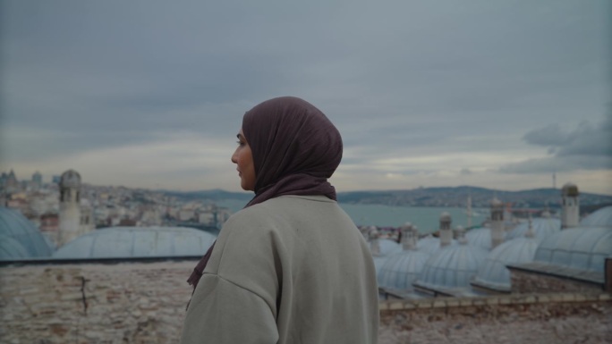 WS城市宁静:戴头巾的妇女在屋顶上凝视伊斯坦布尔的天际线#Istanbul -远景#Cityscap