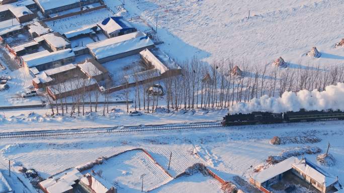 航拍中国东北冬季雪景中的蒸汽火车穿过村庄